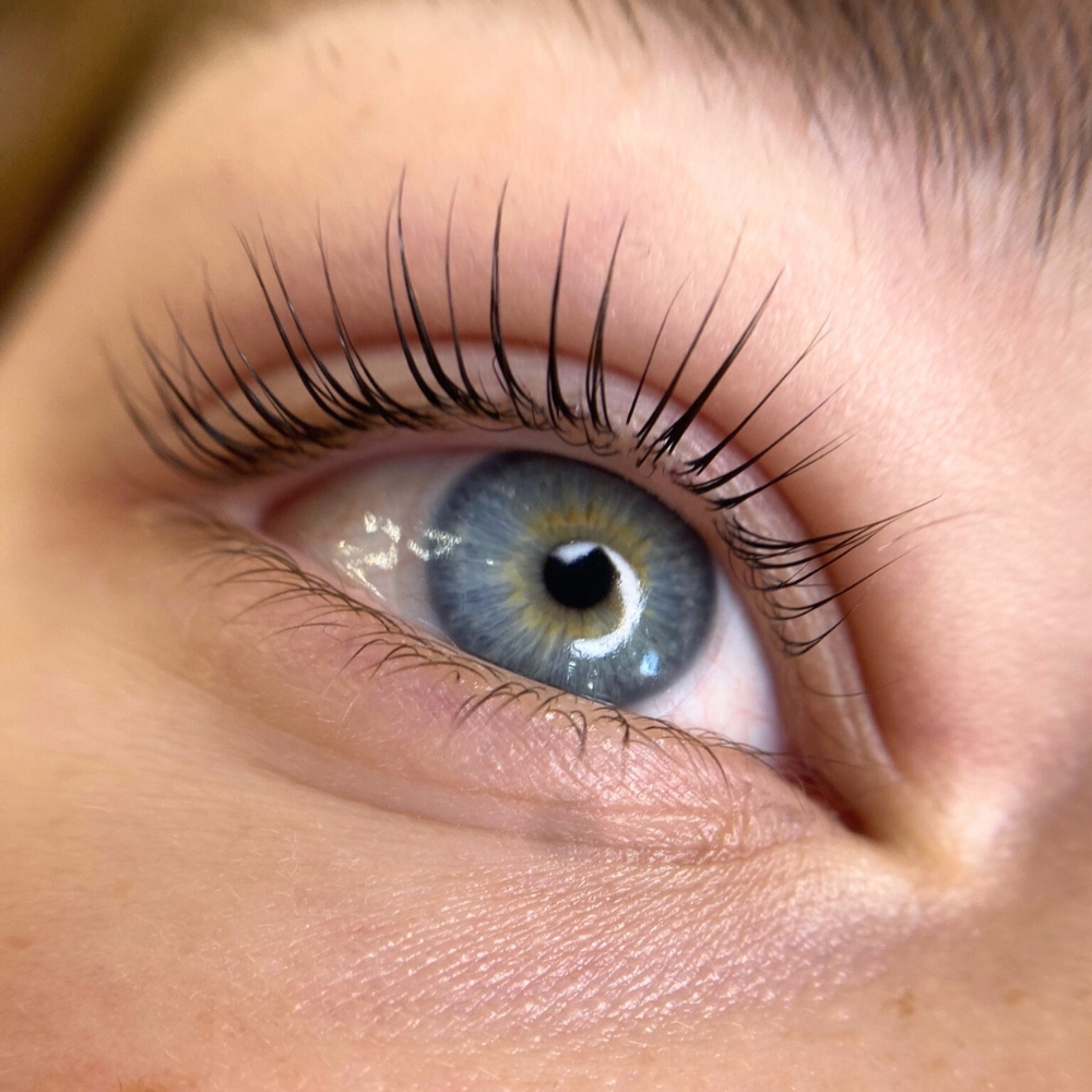 The image captures a close-up of an eye after a lash lift treatment, showcasing the enhanced curl and separation of the eyelashes, which accentuates the eye's natural beauty and color. The treatment gives the lashes a lifted and lengthened appearance without the need for extensions or heavy makeup.