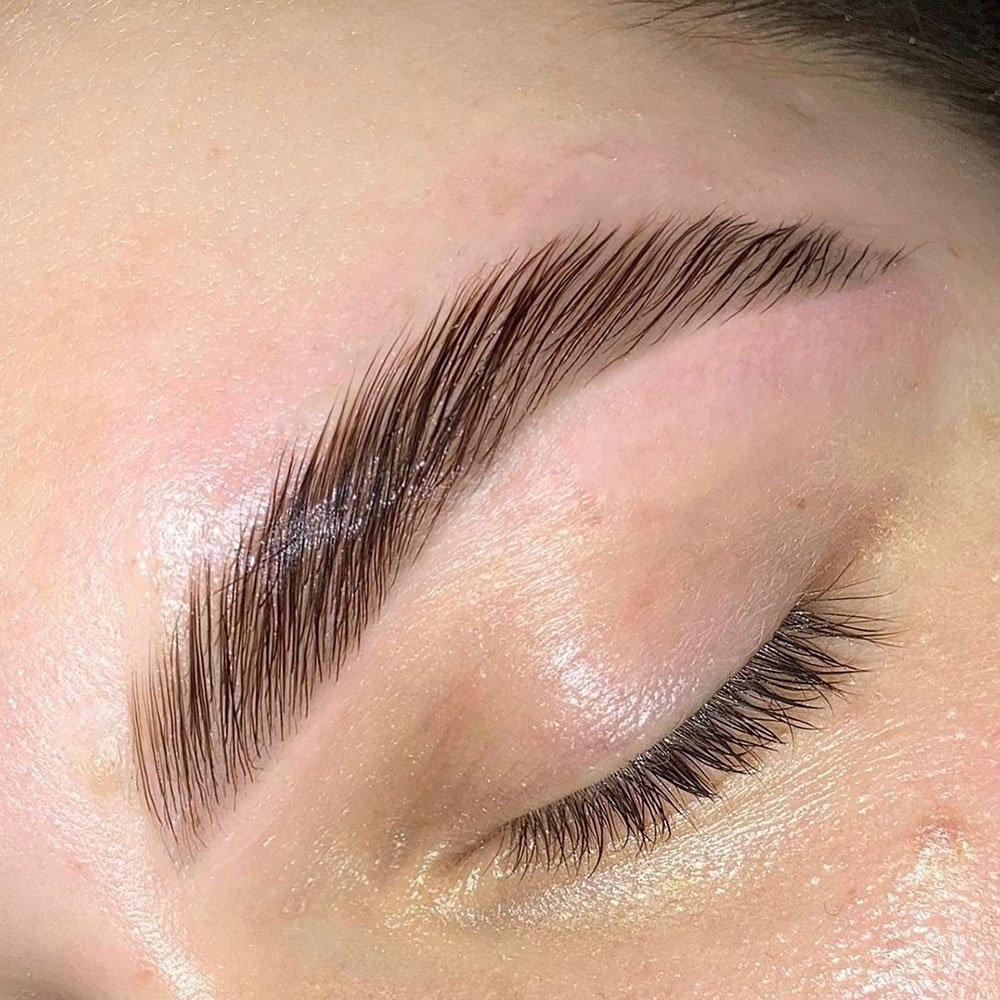 The close-up image showcases an eyebrow that has undergone the brow lamination process, revealing neatly aligned hairs that create a smooth, uniform look. This treatment restructures the brow hairs to keep them in a desired shape, adding fullness and definition.